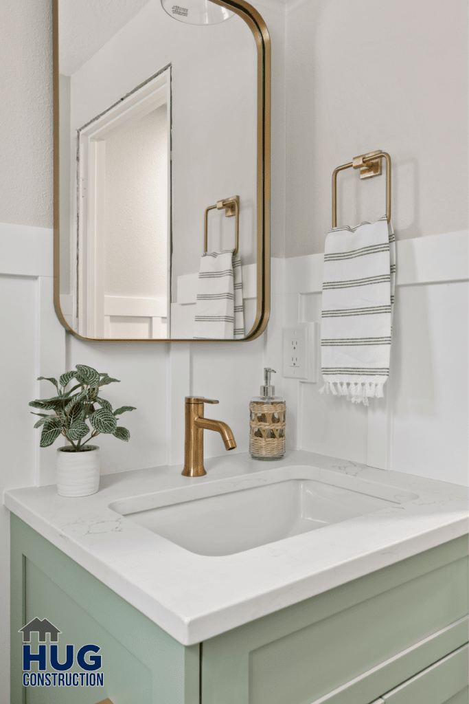 A modern Gunning Rd Interior Remodel bathroom featuring a white countertop with an integrated sink, bronze fixtures, and a rectangular mirror with rounded corners. A striped towel hangs on the wall and a p