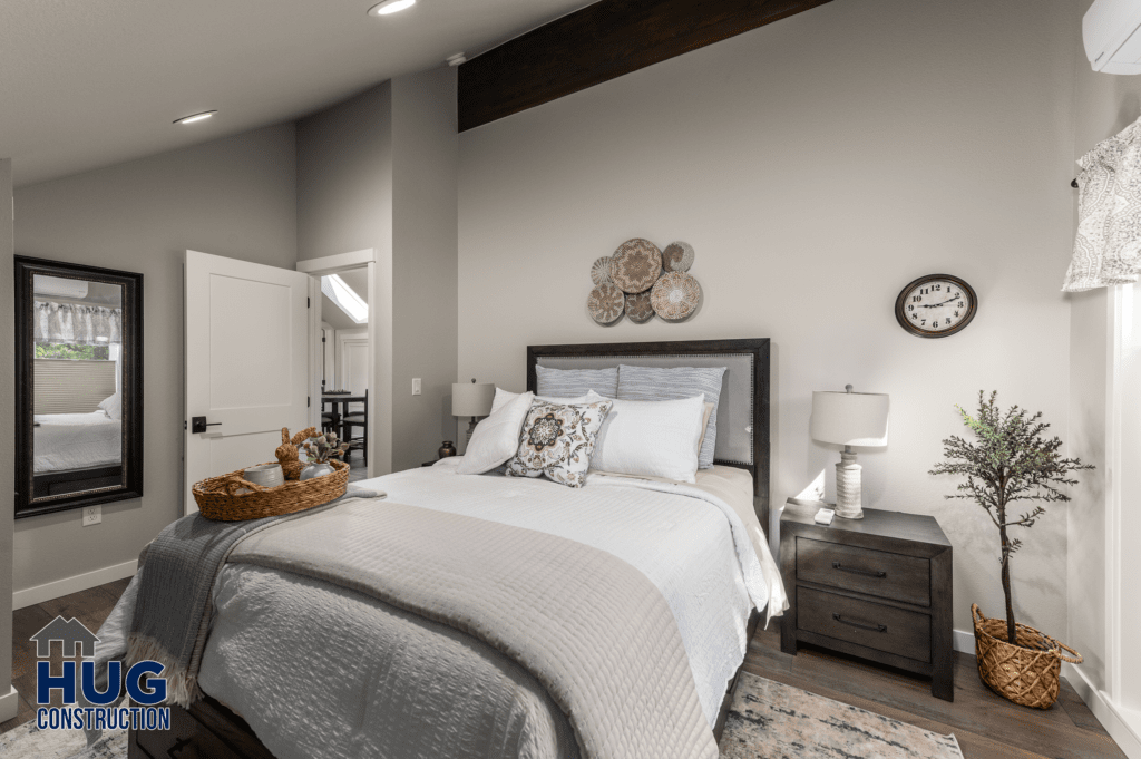 A neatly arranged bedroom featuring a made bed with decorative pillows, two nightstands with lamps, a wall clock, and various decorative accessories from Radio Ln Garage & ADU, with a focus on a neutral