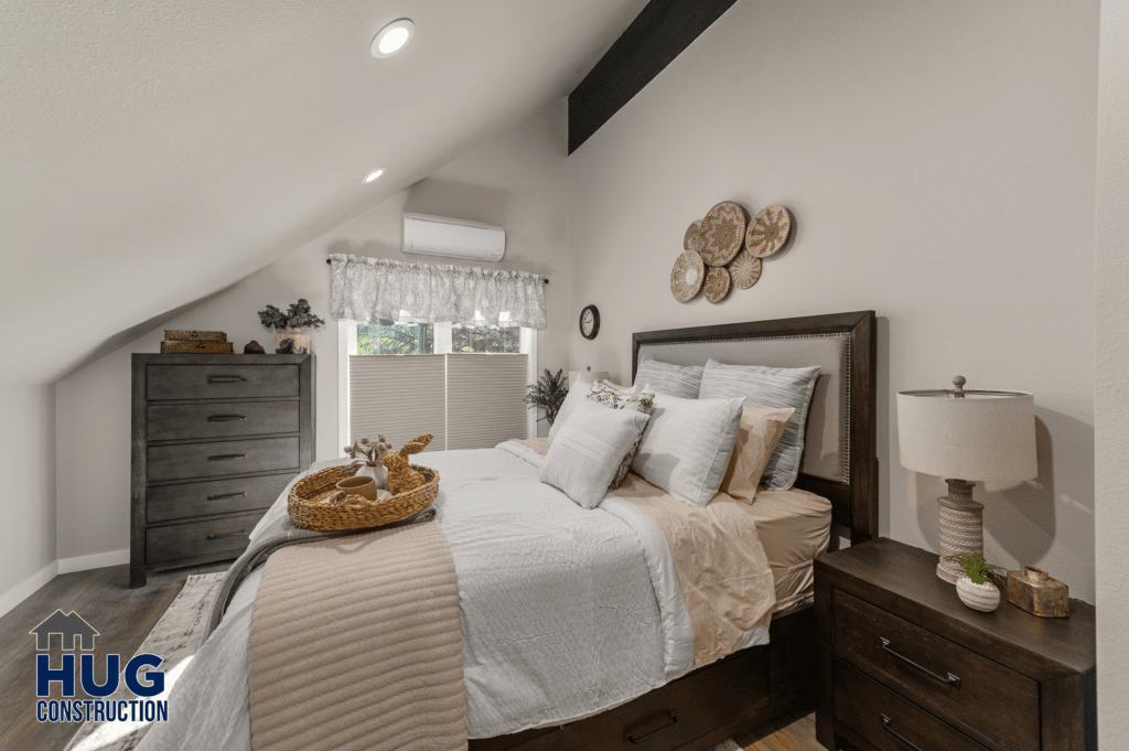 A neatly arranged bedroom featuring a bed with white and beige bedding, a dark wood headboard, side tables with lamps, a dresser, and decorative items from Radio Ln Garage & ADU, set under