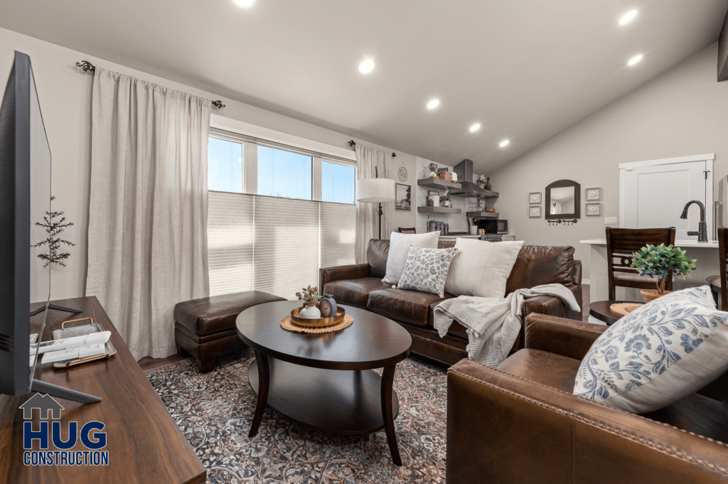 A well-appointed living room featuring a leather sofa, matching armchair, a round wooden coffee table, and decorative elements neatly arranged in a clean and modern space at Radio Ln Garage & ADU.