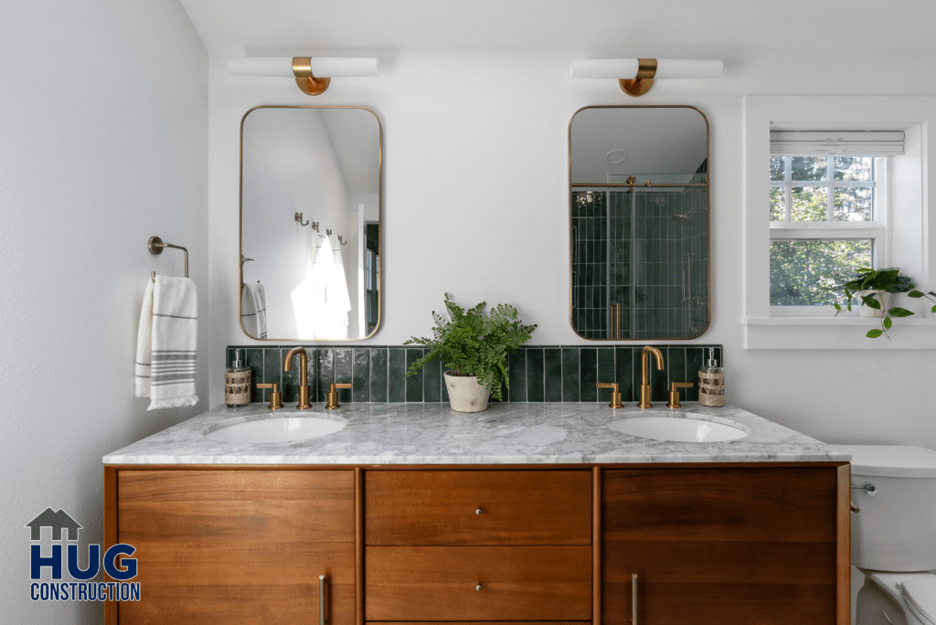 A modern kitchen expansion featuring a wooden vanity with a white countertop, two rectangular mirrors with gold accents, gold fixtures, and a green tiled backsplash.