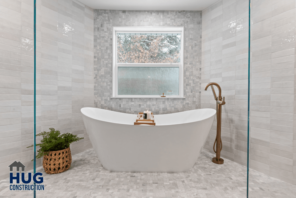 A modern bathroom from the Gunning Rd Interior Remodel featuring a freestanding bathtub with a brass faucet, set in front of a window with a snowy view, accented by neutral tiles and a
