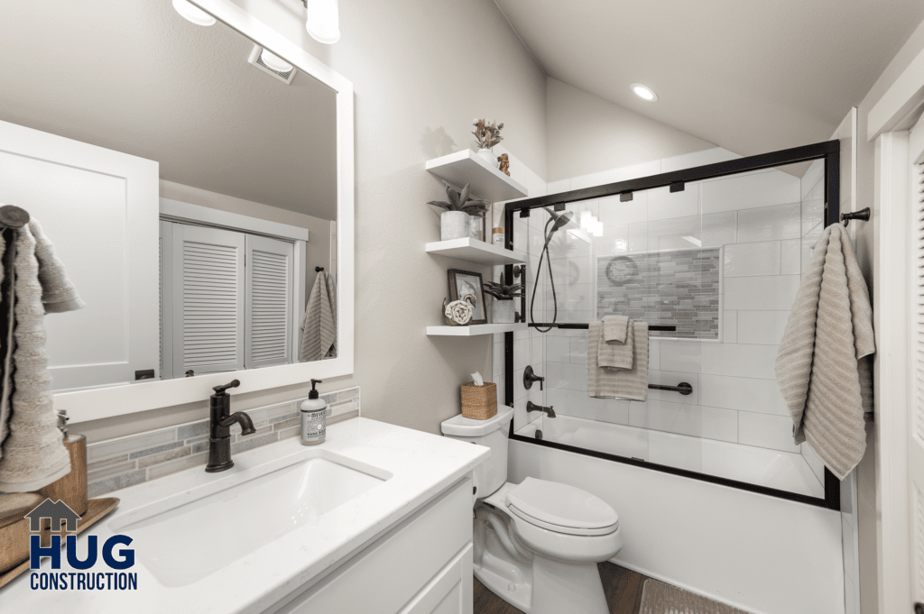 A modern bathroom with white walls, a large mirror, a glass shower enclosure, and well-organized decorations on floating shelves is part of the Radio Ln Garage & ADU.