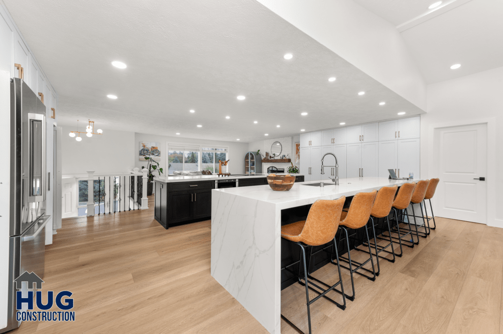 Modern kitchen interior with a white and black color scheme, featuring a large kitchen island with a marble countertop and bar stools, white cabinets, stainless steel appliances, and designed as part of a 2