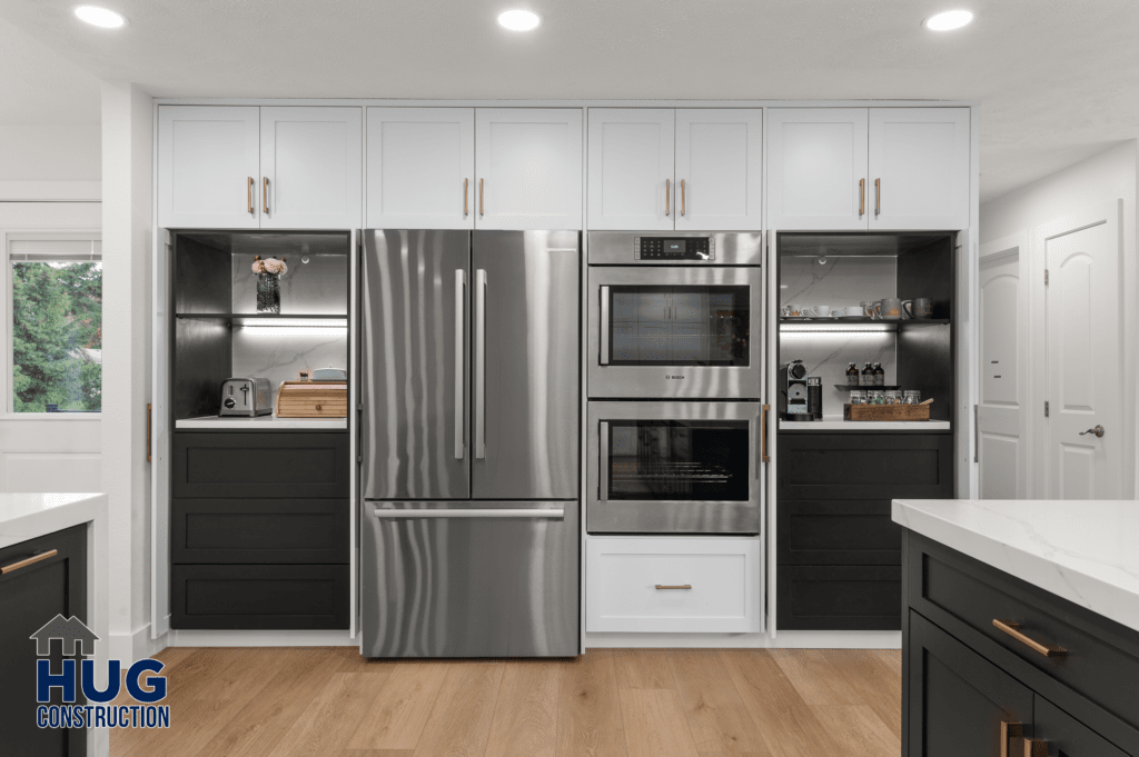 A modern kitchen remodel featuring stainless steel appliances, white cabinetry, and black countertops.