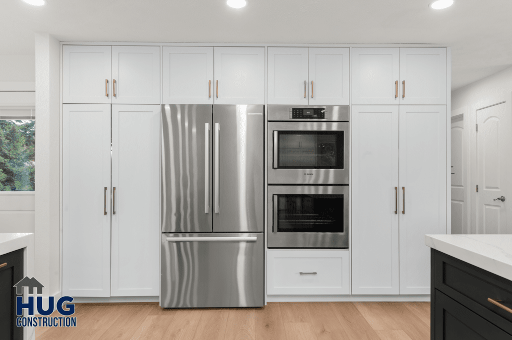 A modern kitchen remodel featuring stainless steel appliances, white cabinetry, and black countertops.